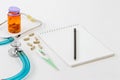 A stethoscope, thermometer, pills and notepad on doctor table or nurse desk