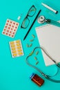 A stethoscope, thermometer, pills, notepad and glasses on doctor table or nurse desk Royalty Free Stock Photo