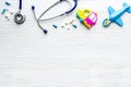 Stethoscope, toys and pills - baby flu and cold concept - on white wooden background top view copy space