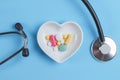 Stethoscope and various pills in a saucer in shape of heart on a blue wooden background Royalty Free Stock Photo