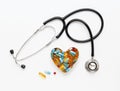 Stethoscope on white background with pills in shape of heart Royalty Free Stock Photo