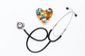 Stethoscope on white background with pills in shape of heart Royalty Free Stock Photo