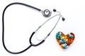 stethoscope on white background with pills in shape of heart Royalty Free Stock Photo