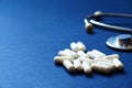 stethoscope and white tablets scattered on a blue background close-up. Royalty Free Stock Photo