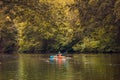 Boy in life jacket doing nature sports canoeing, with a orange canoe on wild river in a autumn color theme. forest scene use as