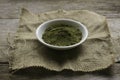 Stevia powder in white plate on rug sack on wooden background