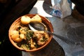 Stew with meat in a clay dish outdoors.