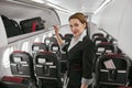 Stewardess near open shelf in cabin of airplane