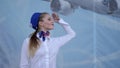 Stewardess salutes in aeroport and smiles looking at camera on blue background