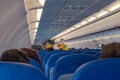 Stewardess in surgical mask and yellow west giving instructions to the passengers. Half empty aircraft due to COVID19