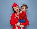 Stewardess wearing in red uniform with a child on hands