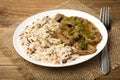 Stewed beef and rice on the white plate on wooden background.