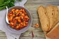 Stewed broad beans in tomato sauce with herbs and spices close-up, slices of rye bread Royalty Free Stock Photo