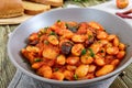 Stewed broad beans in tomato sauce with herbs and spices close-up, slices of rye bread Royalty Free Stock Photo