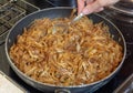 Stewed cabbage is cooked in a frying pan, stirring with a spoon, close-up