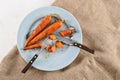 stewed carrots with honey, whole and cut into pieces on a blue plate