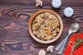 Stewed diced turkey with mushrooms in a creamy sauce in a clay plate on a brown wooden background. Turkey recipes