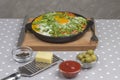 Stewed eggs and vegetables in a pan, shakshouka for breakfast. Cheese, grater, olives, peppers