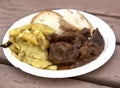 Stewed horse meat with potatoes and bread. Traditional maltese cuisine. Horse meat on white plastic plate served with maltese sour