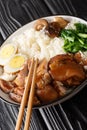 Stewed pork leg with rice, eggs and herb Thai Khao Kha Moo closeup in the bowl. Vertical Royalty Free Stock Photo
