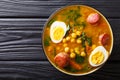 Stewed Potaje de garbanzos chickpeas, spinach, chorizo sausages, boiled eggs close-up in a bowl. horizontal top view