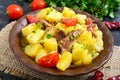 Stewed potatoes with meat in a ceramic bowl on a wooden table