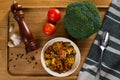Stewed tomatoes with broccoli in a plate on a wooden background