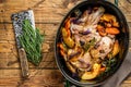 Stewed whole lamb shoulder in a baking dish. Wooden background. Top view