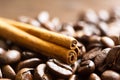 A stick of cinnamon lies on the roasted coffee beans close-up - fragrant macro backgrounds. Brown arabica coffee beans are