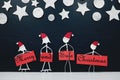 Stick man family figure wearing santa hat holding a red Merry and Safe Christmas greeting banner.