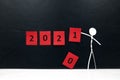 Stick man figure changing 2020 year red cubes to 2021 in black background with copy space. New Year celebration concept. Royalty Free Stock Photo