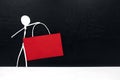 Stick man figure holding blank red signage template in dark background with copy space. Black friday sale and discount sign tag. Royalty Free Stock Photo