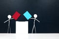 Stick man figure holding red and blue paper ballot beside a vote box. US presidential election democrat versus republican. Royalty Free Stock Photo