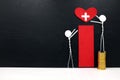 Stick man figure reaching for a red heart shape with cross cutout while stepping on stack of coins. Health, healthcare, medical.