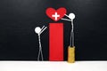 Stick man figure reaching for a red heart shape with cross cutout while stepping on stack of coins. Health, healthcare, medical.