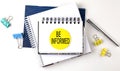 Sticker with BE INFORMED text on notebooks on the white background