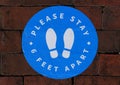 The sticker on the brick walkway asking the customers to stay 6 feet apart