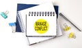 Sticker with MANAGE CONFLICT text on notebooks on the white background