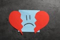 Sticker with sad face and broken heart on grey background, flat lay Royalty Free Stock Photo