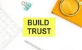 Sticker with the text BUILD TRUST on a white background, near calculator and notebook Royalty Free Stock Photo