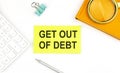 Sticker with the text GET OUT OF DEBT on a white background, near calculator and notebook Royalty Free Stock Photo