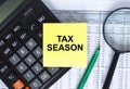 Sticker with text Tax Season lying on the calculator. Magnifying glass with green pen on financial documents Royalty Free Stock Photo