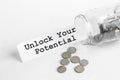 Sticking out of a jar of coins a piece of paper with a text Unlock Your Potential on a white background Royalty Free Stock Photo