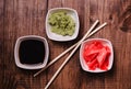 Sticks, Wasabi, soy sauce and pickled ginger for sushi on brown wooden table background. Top view Royalty Free Stock Photo