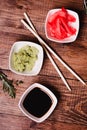 Sticks, Wasabi, soy sauce and pickled ginger for sushi on brown wooden table background. Top view Royalty Free Stock Photo