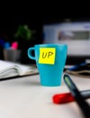 Sticky note on a coffe cup at office desk. Wake up Royalty Free Stock Photo