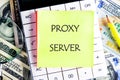 A sticky note labeled proxy server is placed on a calculator surrounded by currency notes, symbolizing technology's