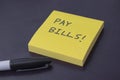 Sticky note pad with the reminder to pay bills