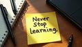 Sticky note on table reads Never Stop Learning near notepad. Concept of ongoing personal growth, knowledge, career. Modern Royalty Free Stock Photo