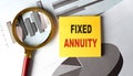 Sticky note with the text fixed annuity , placed on financial charts with a magnifying glass and red handle Royalty Free Stock Photo